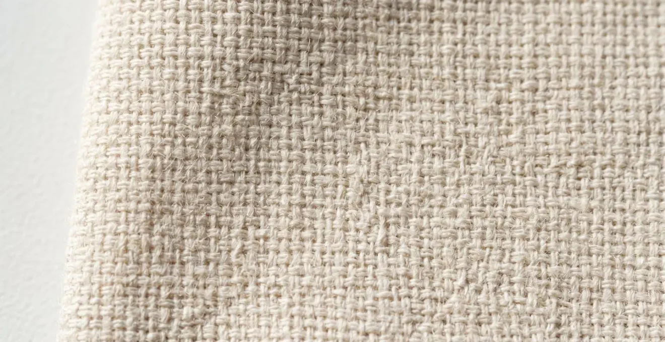 Vue rapprochée d'une texture de tissu montrant une trame serrée avec des fibres naturelles visibles